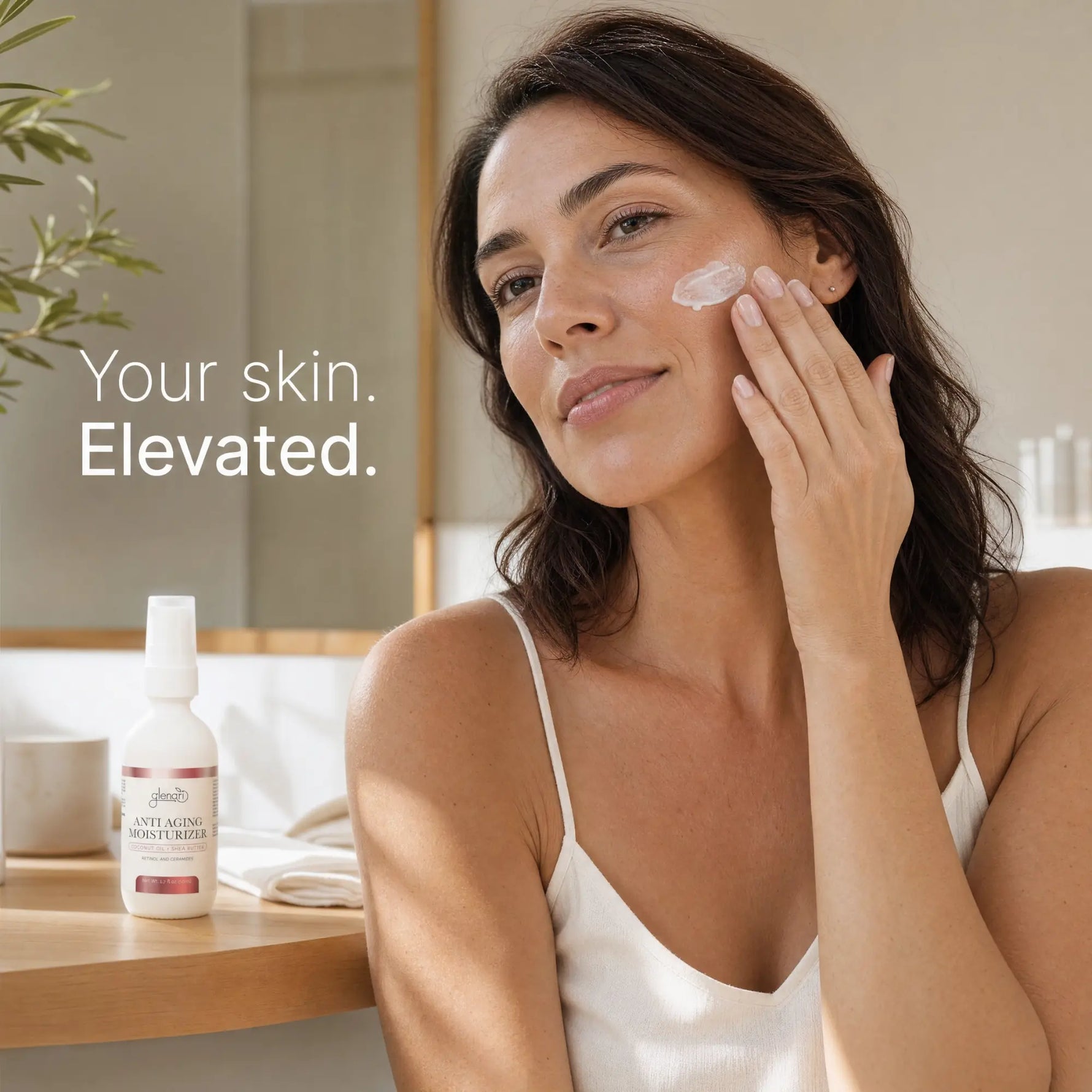 A woman in a white camisole applies cream to her cheek in a bright bathroom setting. A bottle of Glenari Anti-Aging Moisturizer is visible on the counter beside her, with the text 'Your skin. Elevated.'