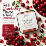 A square tin of Glenari Energy Strips vitamin supplement arranged on a light surface with scattered red cranberries and promotional text. The tin is white with copper-toned bands and black text, and the image includes a bowl of cranberries and a callout box describing the flavor and product benefits.