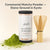 Glenari ceremonial matcha powder in a white cylindrical container with a black lid, shown beside a bamboo whisk and a small pile of bright green matcha powder on a warm beige background. Text at the top reads 'Ceremonial Matcha Powder — Stone-Ground in Kyoto'.