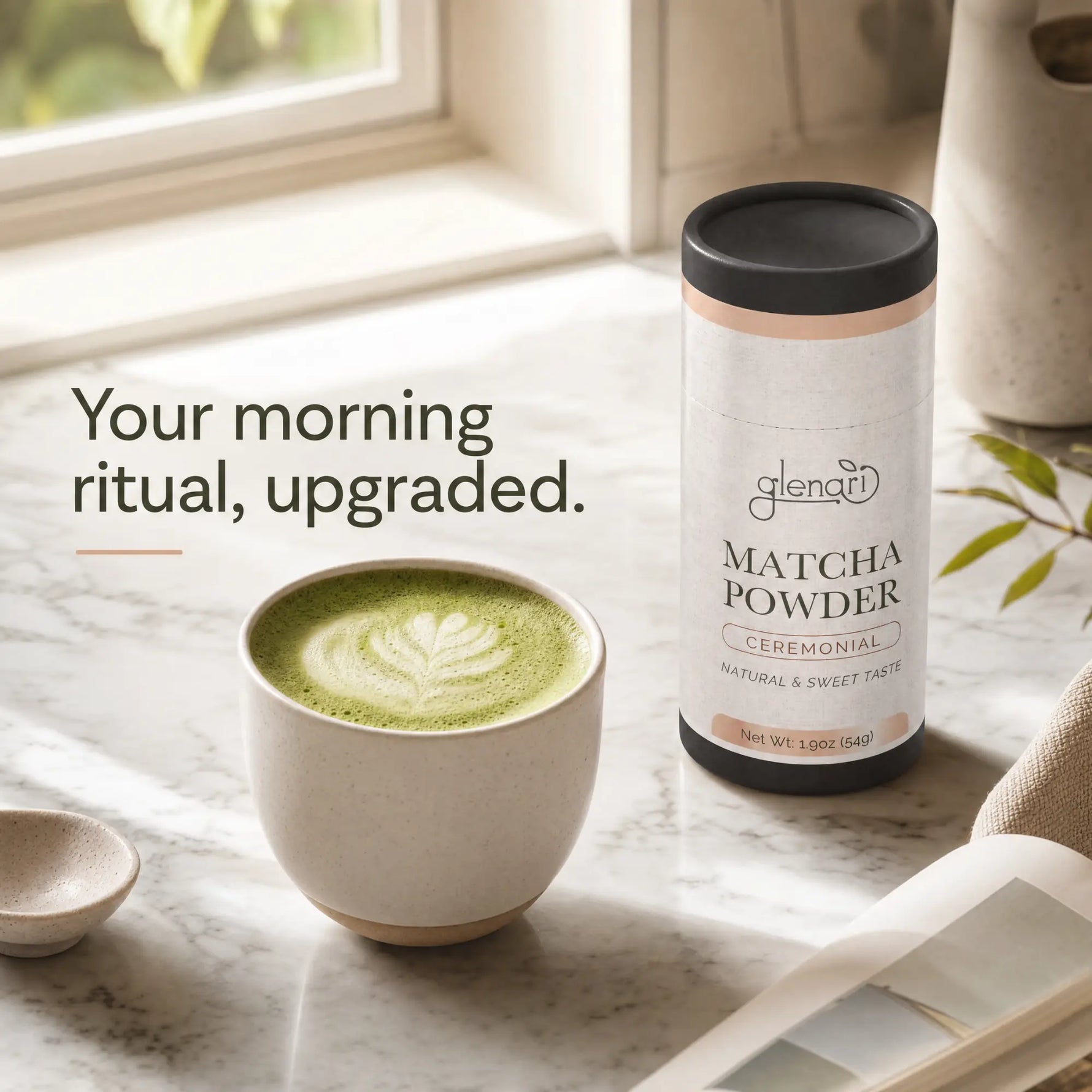 A bottle of Glenari ceremonial matcha powder stands on a marble surface beside a cup of green matcha latte with leaf art foam, with text reading 'Your morning ritual, upgraded.' in a softly lit kitchen setting.