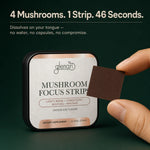 A hand holds a brown mushroom focus strip in front of a square tin labeled Glenari Mushroom Focus Strips. The background is dark green, with marketing text at the top reading '4 Mushrooms.