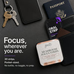 A flat-lay product shot of Glenari Mushroom Focus Strips in a pocket-sized square tin, surrounded by lifestyle props including a passport, wallet, keys, and phone on a dark textured background. Text on the left reads 'Focus, wherever you are.