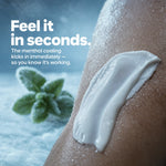 A close-up of a person's leg with a thick white cream applied, alongside text reading 'Feel it in seconds.' and a small mint leaf graphic on a cool blue background.
